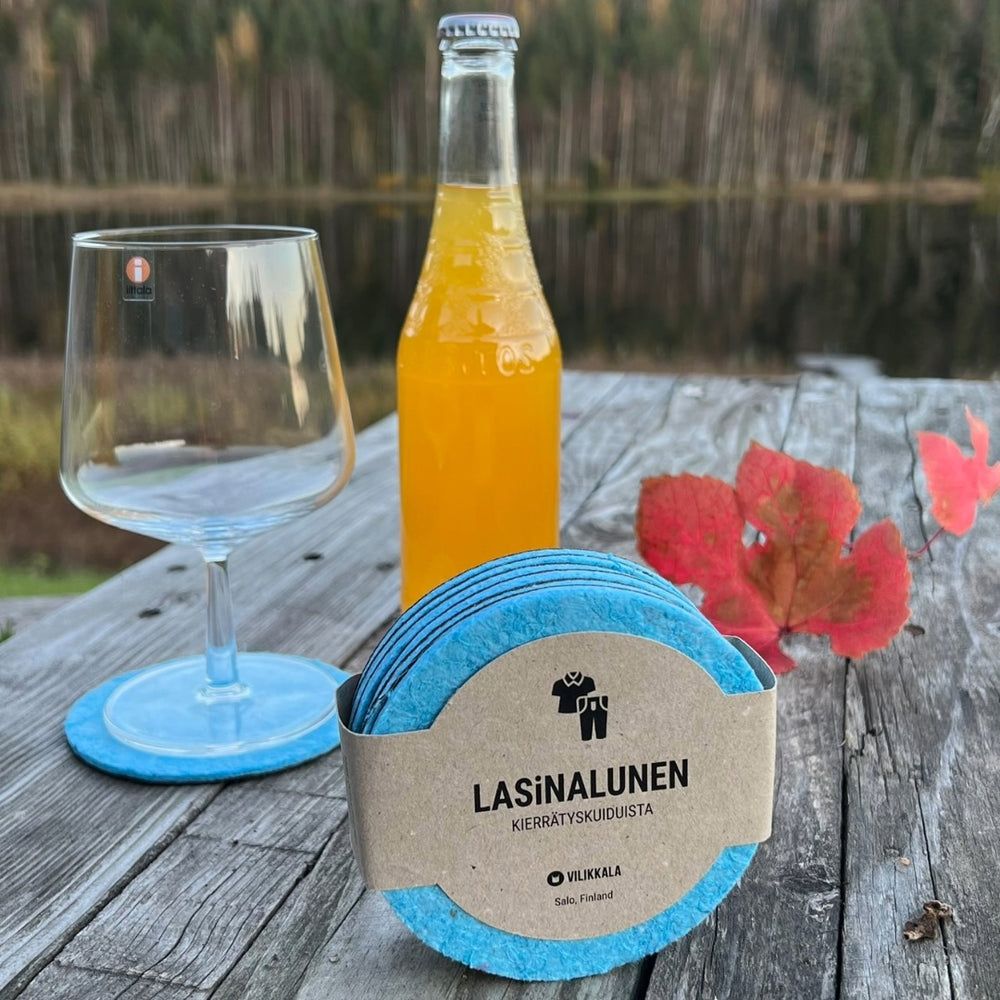Lasinalunen kierrätyskuitu VIIARI esille asetettu lasin ja limonadipullon vieressä ulkona.