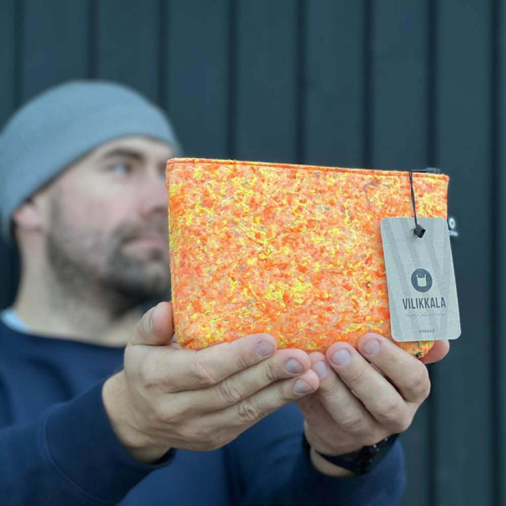 Tarvikepussi poistotekstiilihuopa METSÄJAANU oranssi säilytyspussi käsissä
