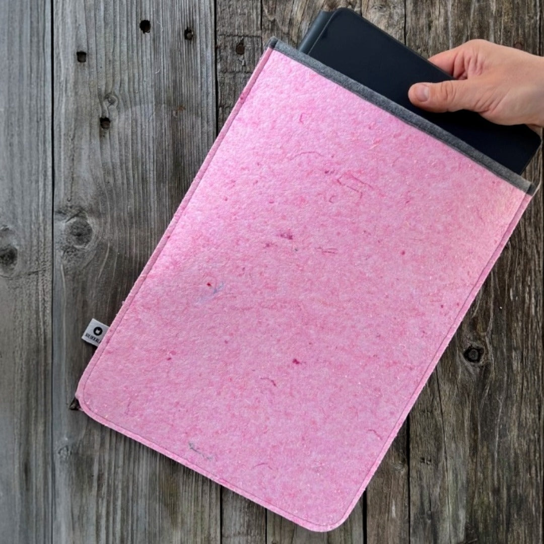 14 tuuman läppärisuoja tietokoneelle pinkki-harmaa kädessä puupinnalla.